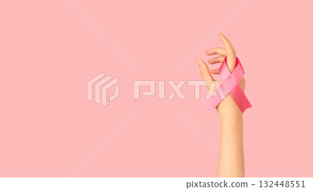 International symbol of Breast Cancer Awareness Month in October. Close up of female hand holding satin pink ribbon awareness on pink background. Women's health care and medical concept. 132448551