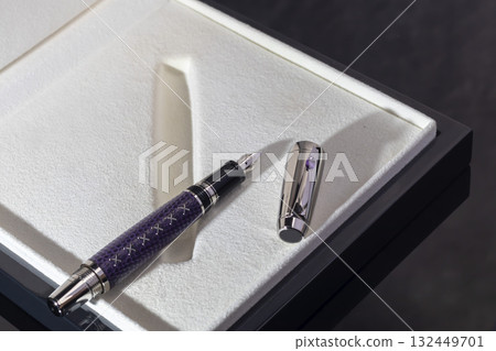 A signature fountain pen on a gray marble background. A box and case are nearby. A signature fountain pen on a gray marble background. A box and case are nearby. 132449701