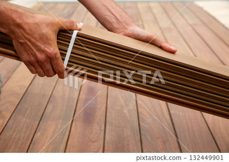 Ipe deck installation carpenter hands holding wood 132449901