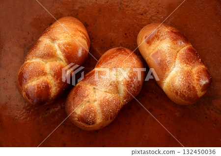 Three brioche pastries over orange clay Three brioche pastries over orange clay 132450036
