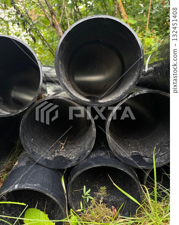 Pile of black pipes are stacked on top of each other 132451408