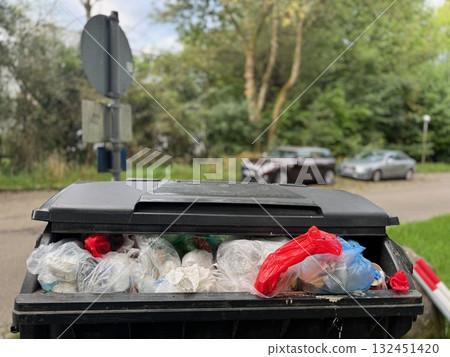 Trash can is full of plastic bags and bottles 132451420