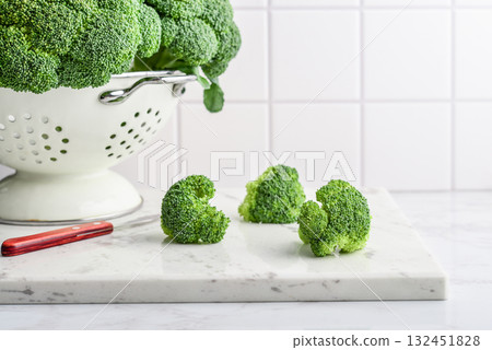 Raw broccoli in a white enamel colander Raw broccoli in a white enamel colander 132451828