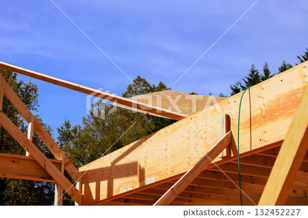 Construction workers install roof materials on wooden beams frame in suburban neighborhood 132452227