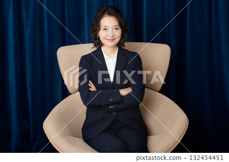 Middle-aged businesswoman sitting on a large chair Middle-aged businesswoman sitting on a large chair 132454451