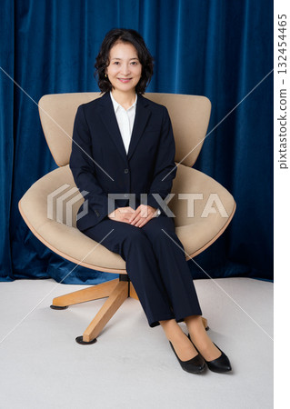 Middle-aged businesswoman sitting on a large chair Middle-aged businesswoman sitting on a large chair 132454465