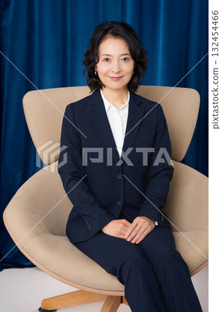 Middle-aged businesswoman sitting on a large chair Middle-aged businesswoman sitting on a large chair 132454466