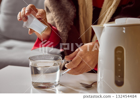 Senior woman pouring soluble powder from sachet into glass of hot water 132454484