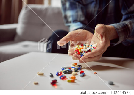 Hands holding handful of mixed colorful pills over white table Hands holding handful of mixed colorful pills over white table 132454524