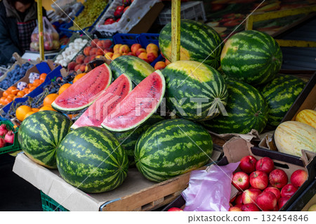 Watermelons and fresh fruits in outdoor market stall and juicy red watermelons cut in half. 132454846