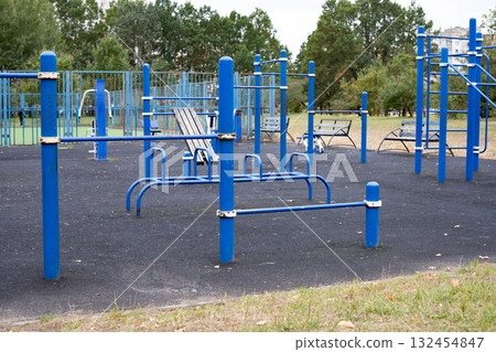 Urban sports ground with exercise equipment near residential buildings. A close-up of various exercise equipment on a playground Urban sports ground with exercise equipment near residential buildings. A close-up of various exercise equipment on a playground 132454847