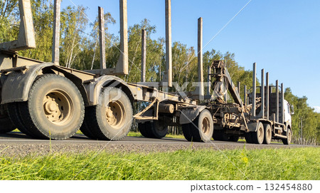 Timber truck with empty trailers and mobile crane on the highway. Timber export and shipping concept Timber truck with empty trailers and mobile crane on the highway. Timber export and shipping concept 132454880