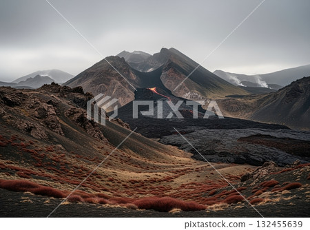 Dramatic volcanic landscape with glowing lava flow and dark mountains under overcast sky 132455639