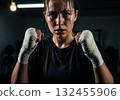 Sweaty female boxer portrait with wrapped hands, intense fighter after workout 132455906
