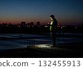 Engineer on construction site at dusk using smartphone, illuminated by screen light 132455913