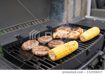 Grilled corn, chicken, and burgers cooking on a backyard bbq grill Grilled corn, chicken, and burgers cooking on a backyard bbq grill 132456417