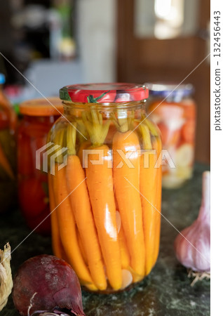 Pickled carrots in jar with fresh vegetables on kitchen counter. National Pickle Day Pickled carrots in jar with fresh vegetables on kitchen counter. National Pickle Day 132456443