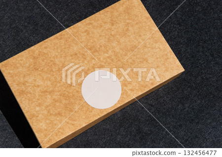 Brown box with white sticker on dark surface in sunlight Brown box with white sticker on dark surface in sunlight 132456477