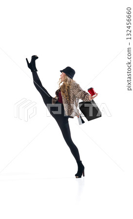 Fashionable woman in leopard jacket lifting leg high with shopping bag and coffee cup Fashionable woman in leopard jacket lifting leg high with shopping bag and coffee cup 132456660