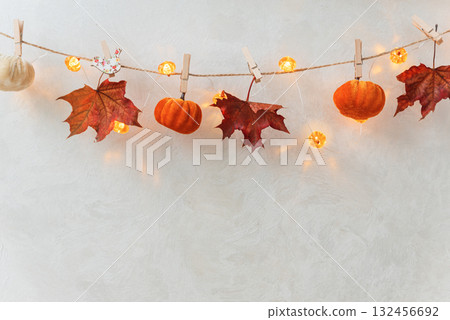 Autumn Garland with Leaves, Pumpkins, Berries, and Lights on Textured Wall Autumn Garland with Leaves, Pumpkins, Berries, and Lights on Textured Wall 132456692