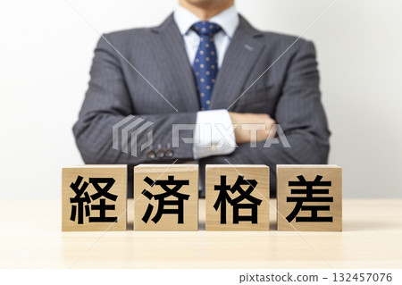 A businessman with his arms crossed and a block that reads "Economic Disparity" 132457076