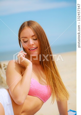Woman on beach talking by mobile phone. 132457347