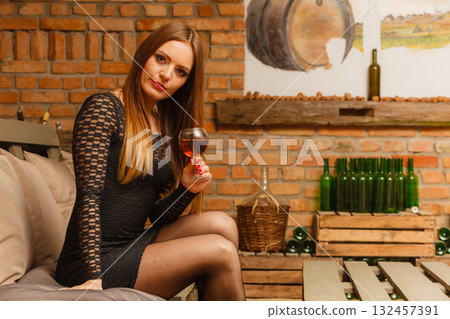 Woman tasting wine in rural cottage interior 132457391