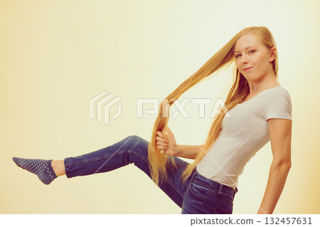 Blonde girl brushing her long hair 132457631
