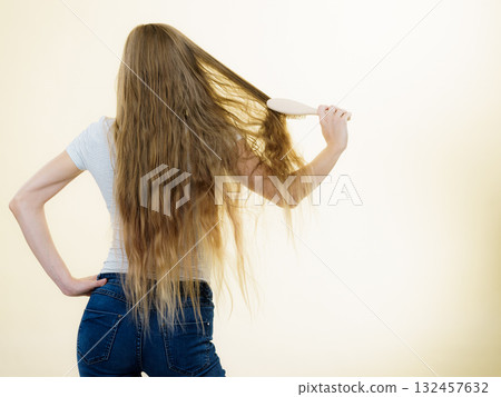 Blonde girl brushing her long hair 132457632