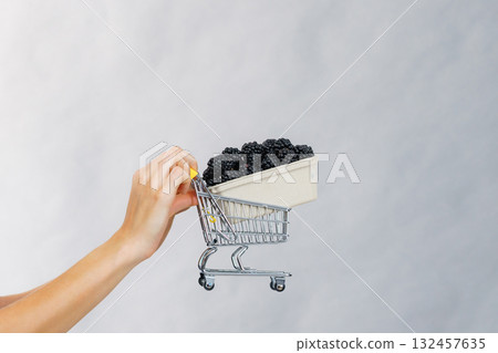 Hand holds blackberry fruits in shopping cart 132457635