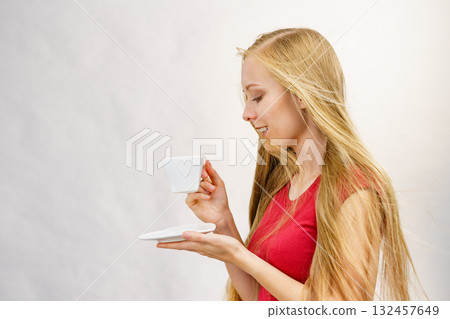 Blonde girl blowing hair holds coffee cup Blonde girl blowing hair holds coffee cup 132457649