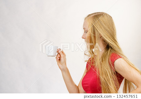 Blonde girl blowing hair holds coffee cup 132457651