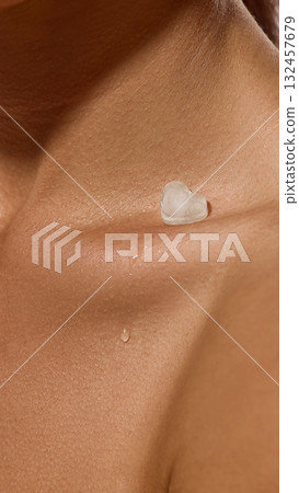 Close-up collarbone with melting ice heart and water drop on skin surface. Close-up collarbone with melting ice heart and water drop on skin surface. 132457679