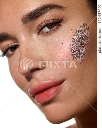 Portrait woman with exfoliating cream and coffee scrub on cheek looking at camera. 132457692