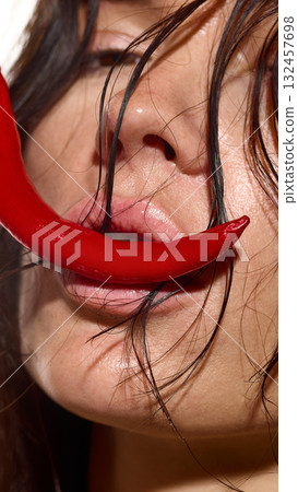 Female lips touching red chili pepper symbolizing intensity and desire 132457698