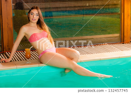 Woman relaxing at swimming pool edge. Leisure. 132457745