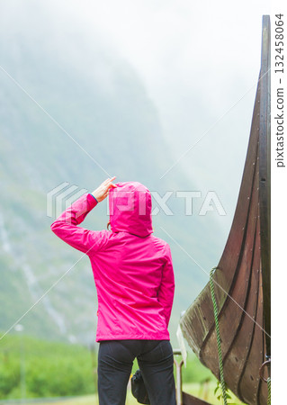 Tourist standing near old wooden viking boat in norwegian nature Tourist standing near old wooden viking boat in norwegian nature 132458064