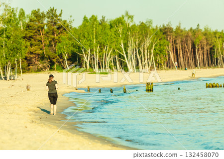 Woman in sportswear running through seaside Woman in sportswear running through seaside 132458070