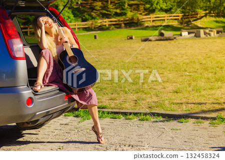 Girl with guitar on hatchback car Girl with guitar on hatchback car 132458324