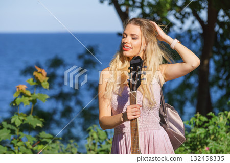 Woman playing acoustic guitar in park Woman playing acoustic guitar in park 132458335