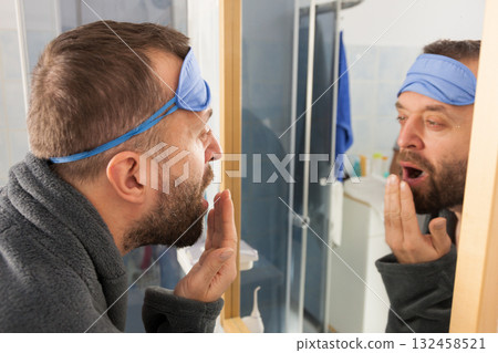 Sleepy man looking at mirror and yawning Sleepy man looking at mirror and yawning 132458521