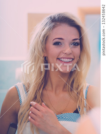 Happy woman fixing her hair Happy woman fixing her hair 132458642