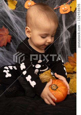Baby in Skeleton Costume with Pumpkin and Leaves Baby in Skeleton Costume with Pumpkin and Leaves 132458976