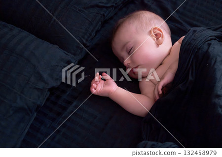 Peaceful baby sleeping on dark bedding 132458979