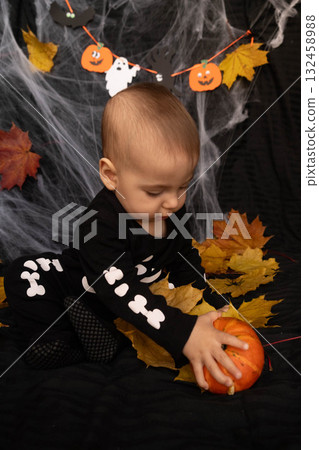 Baby in Skeleton Costume with Pumpkin and Leaves Baby in Skeleton Costume with Pumpkin and Leaves 132458988