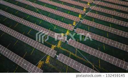 Rows of solar panels on a green field viewed from above, creating a geometric pattern under the sunlight. Rows of solar panels on a green field viewed from above, creating a geometric pattern under the sunlight. 132459145