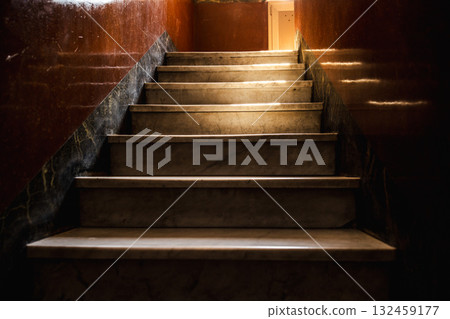 Vintage marble staircase inside an old Roman house with warm sunlight casting dramatic shadows on polished walls 132459177