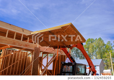 Heavy machinery lifts large wooden OSB panel into place at construction site 132459203