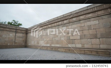 Ancient Stone Wall with Intricate Carvings Under Cloudy Sky 132459741