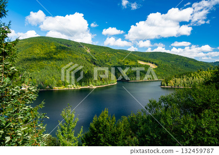 Panoramic view of the Sance reservoir and lake in summer, surrounded by green forests and blue sky, located near the Beskydy mountains in the Czech Republic. Panoramic view of the Sance reservoir and lake in summer, surrounded by green forests and blue sky, located near the Beskydy mountains in the Czech Republic. 132459787